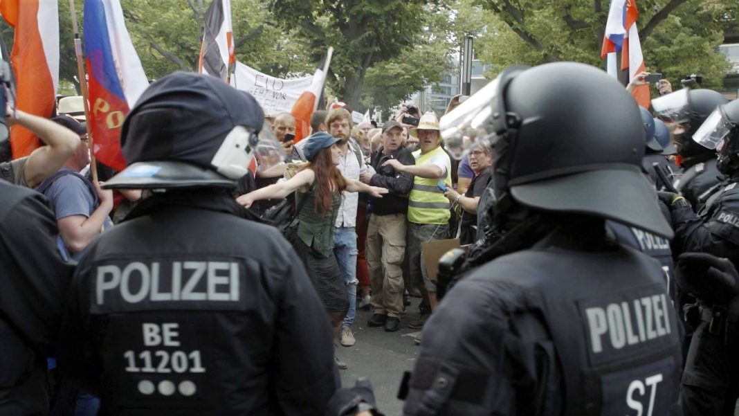 Auf der Querdenken-Demo in Berlin am 29. August 2020 greift eine Demonstrantin schlichtend zwischen Teilnehmenden und Polizei ein. Foto: ZDF / Leo Schmidt
